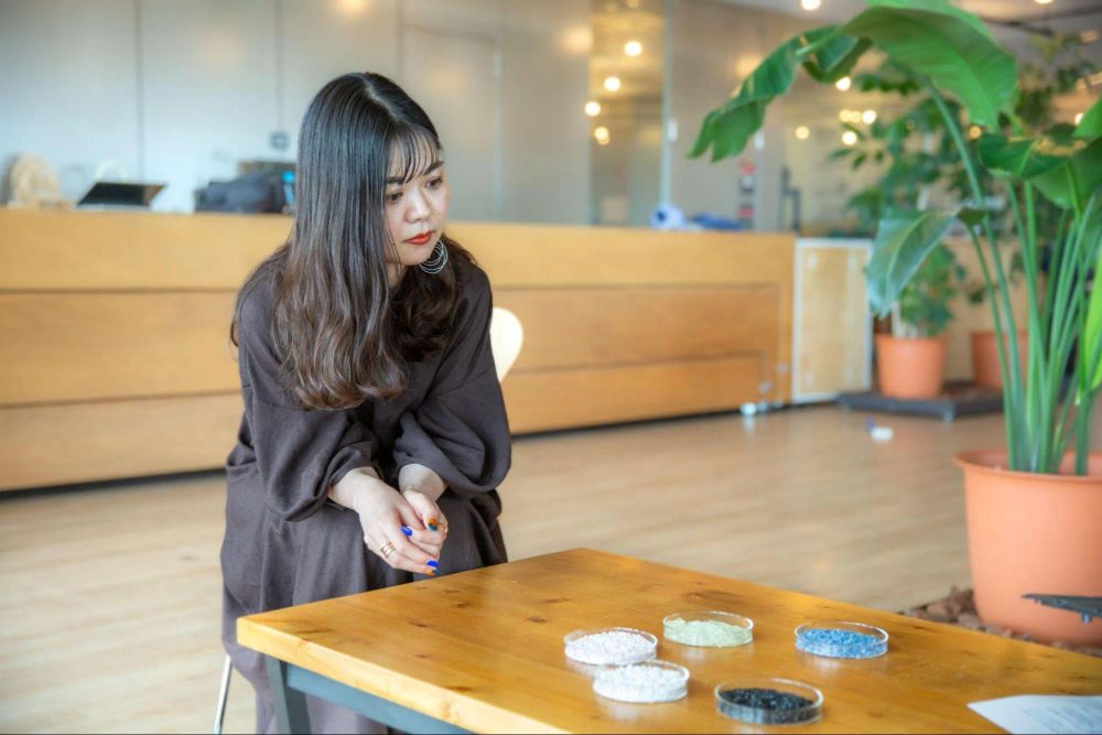 小林 茉莉子さんが再生材の原料のサンプルを見ている様子