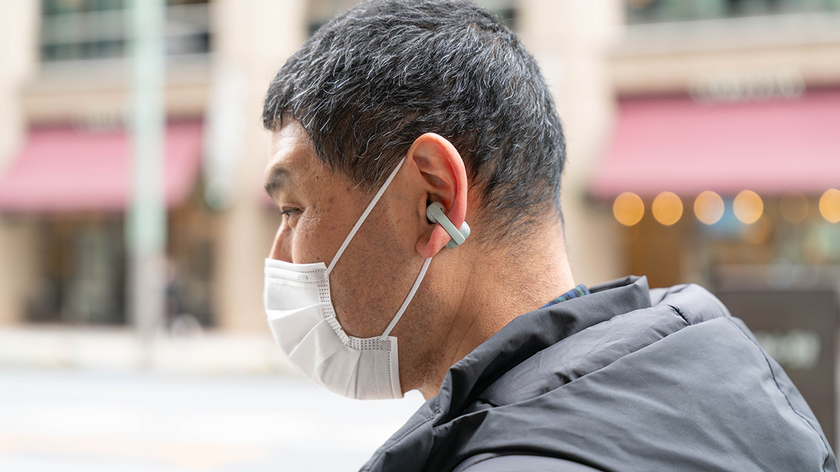 街の中でワイヤレスステレオヘッドセットを装着して歩く人の横顔