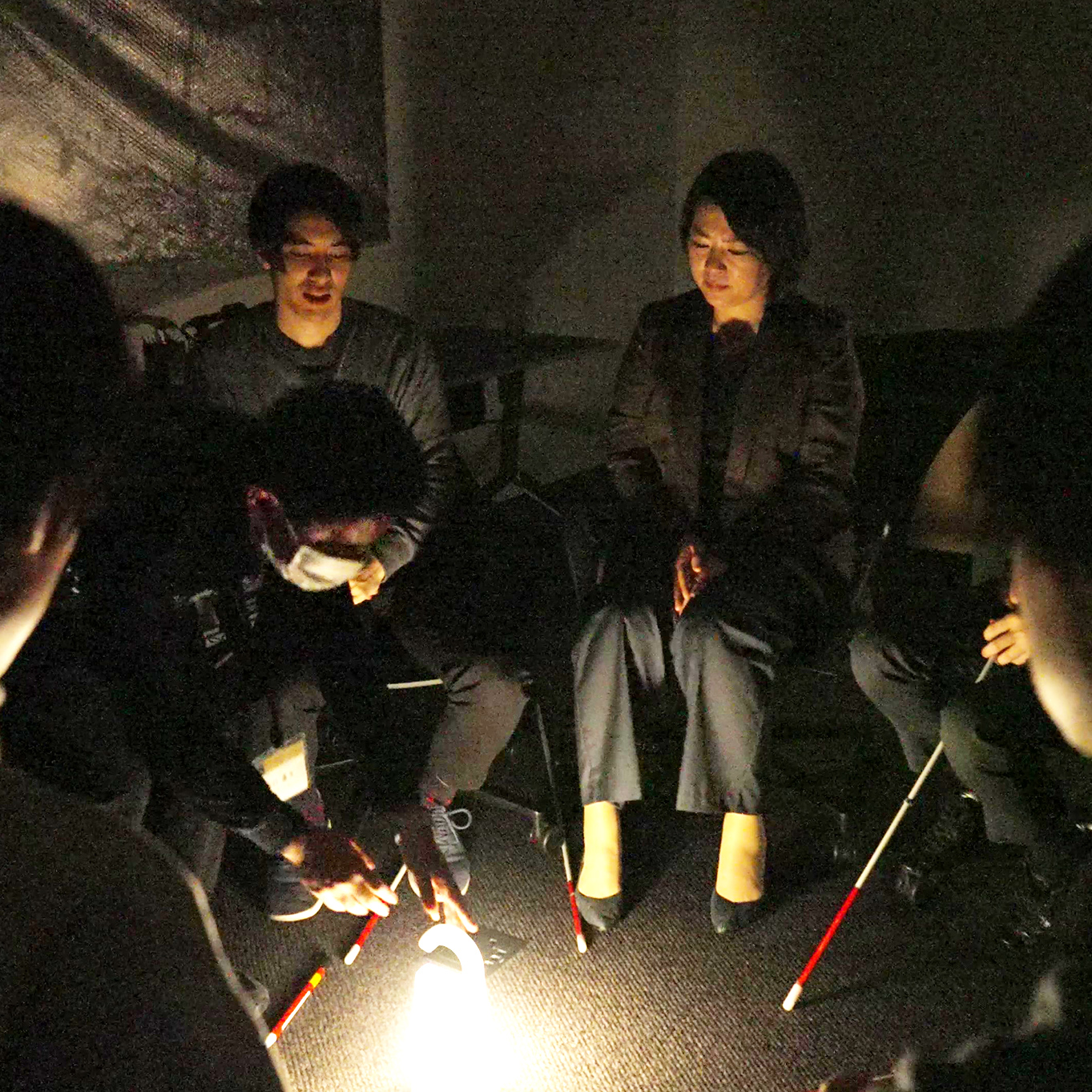 暗闇の中で決められたゴールを目指すワークショップの風景。暗い部屋で参加者が体験をしている。