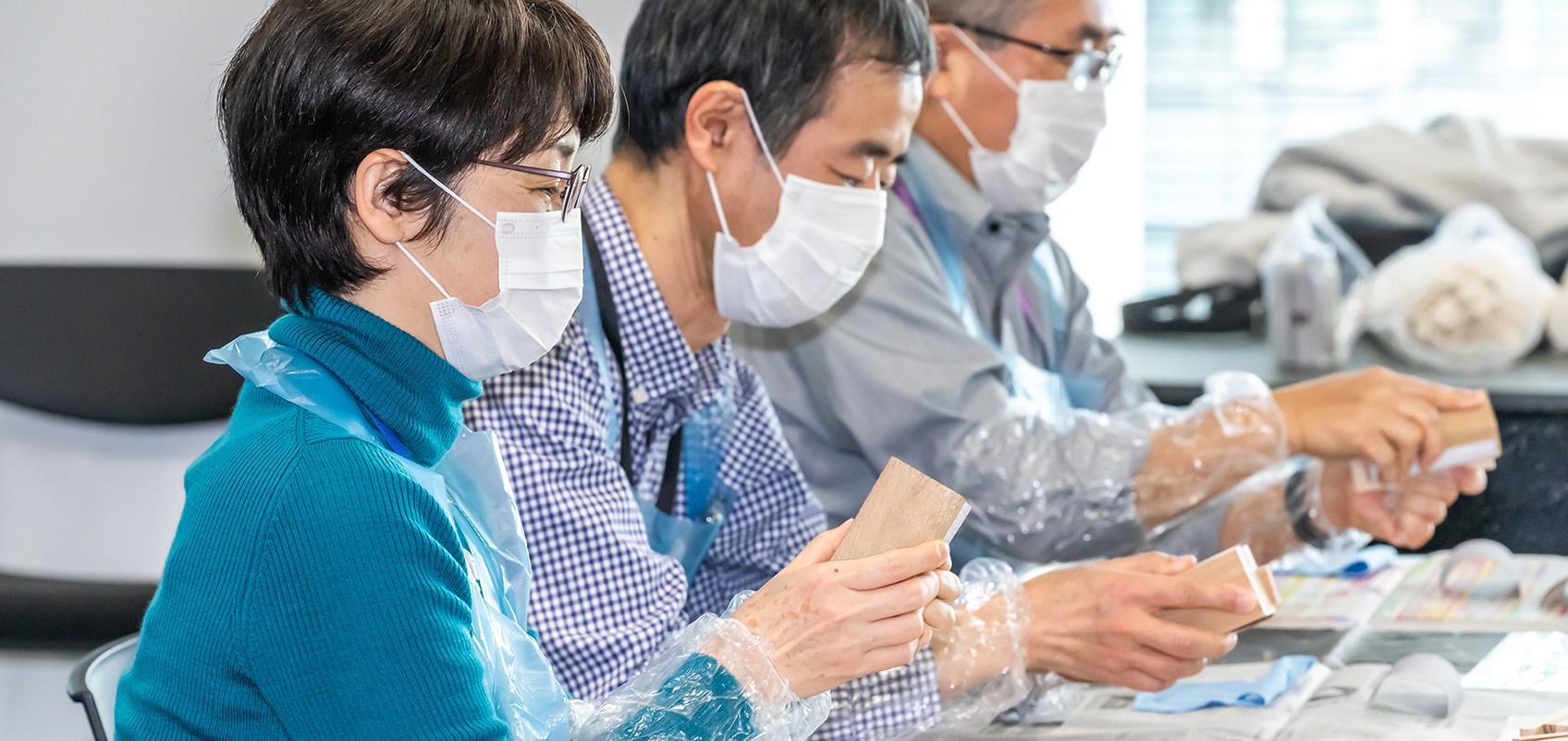 紙やすりを使って木片をみがく人々の写真