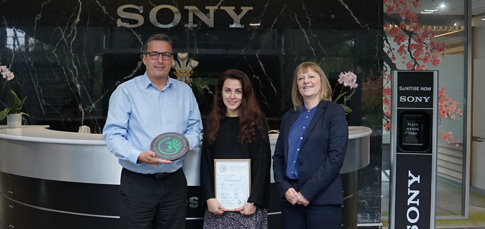 手に賞状などを持った人々の集合写真