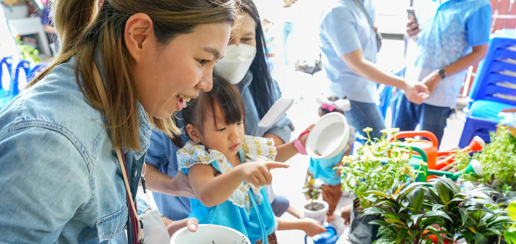 植木鉢を手に持ち、植物を眺める人々の写真