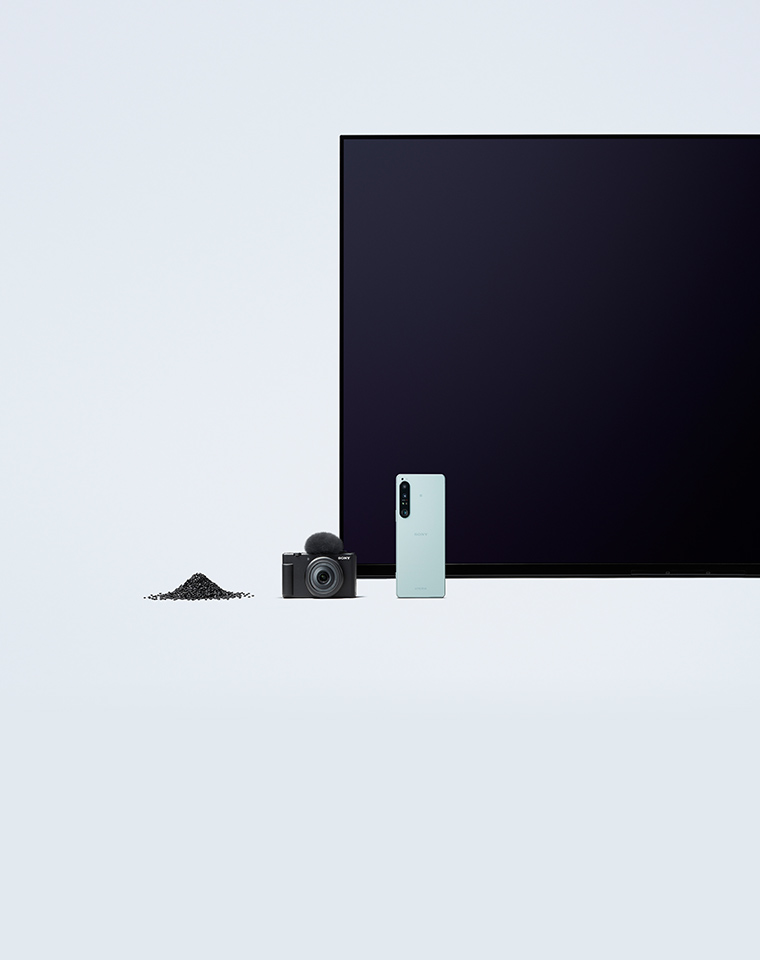 テレビ、カメラ、スマートフォン、黒色のプラスチックペレットを並べた画像