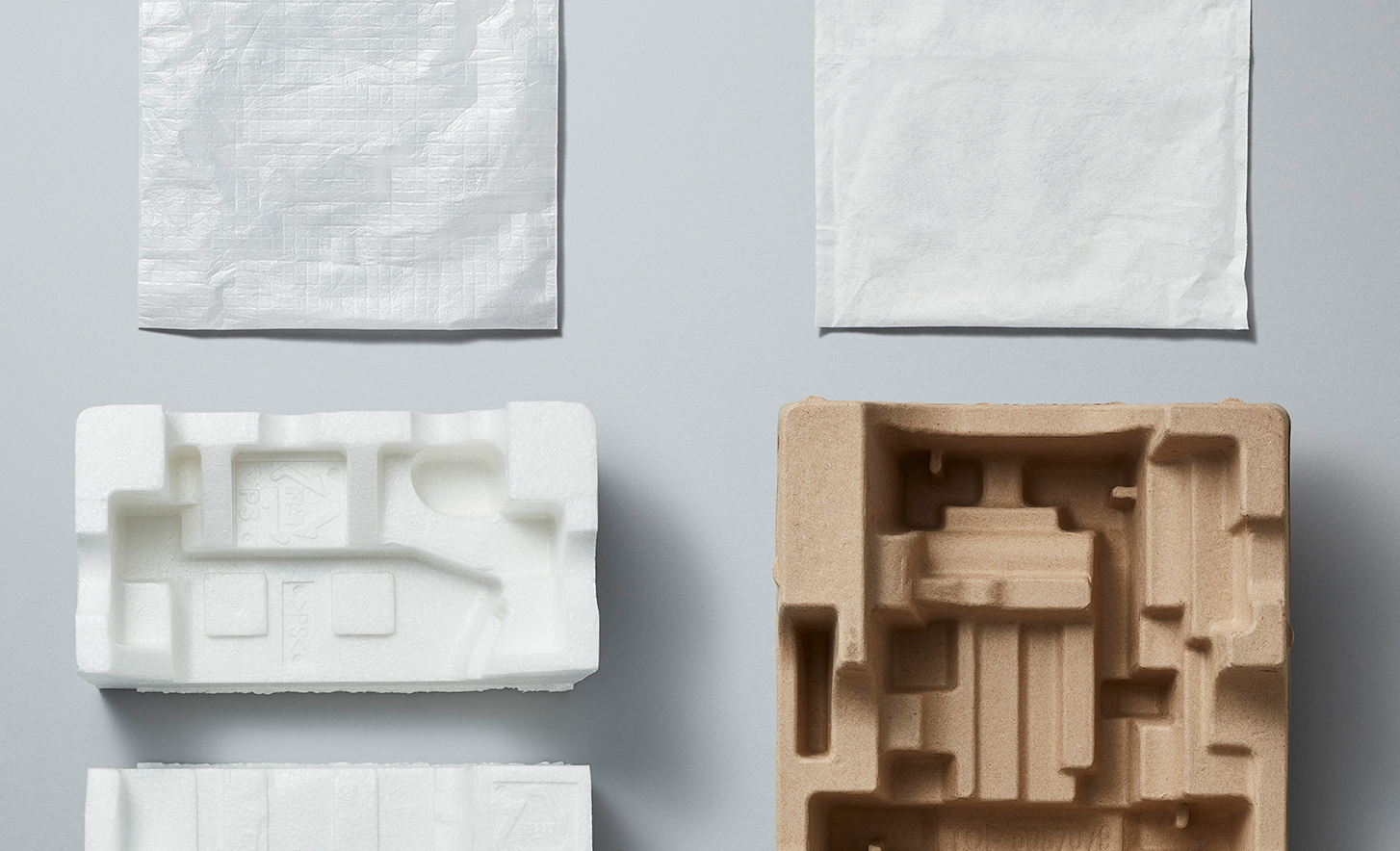 白色の緩衝材（左）と、パルプモールド（右）、不織布の小袋が並ぶ画像