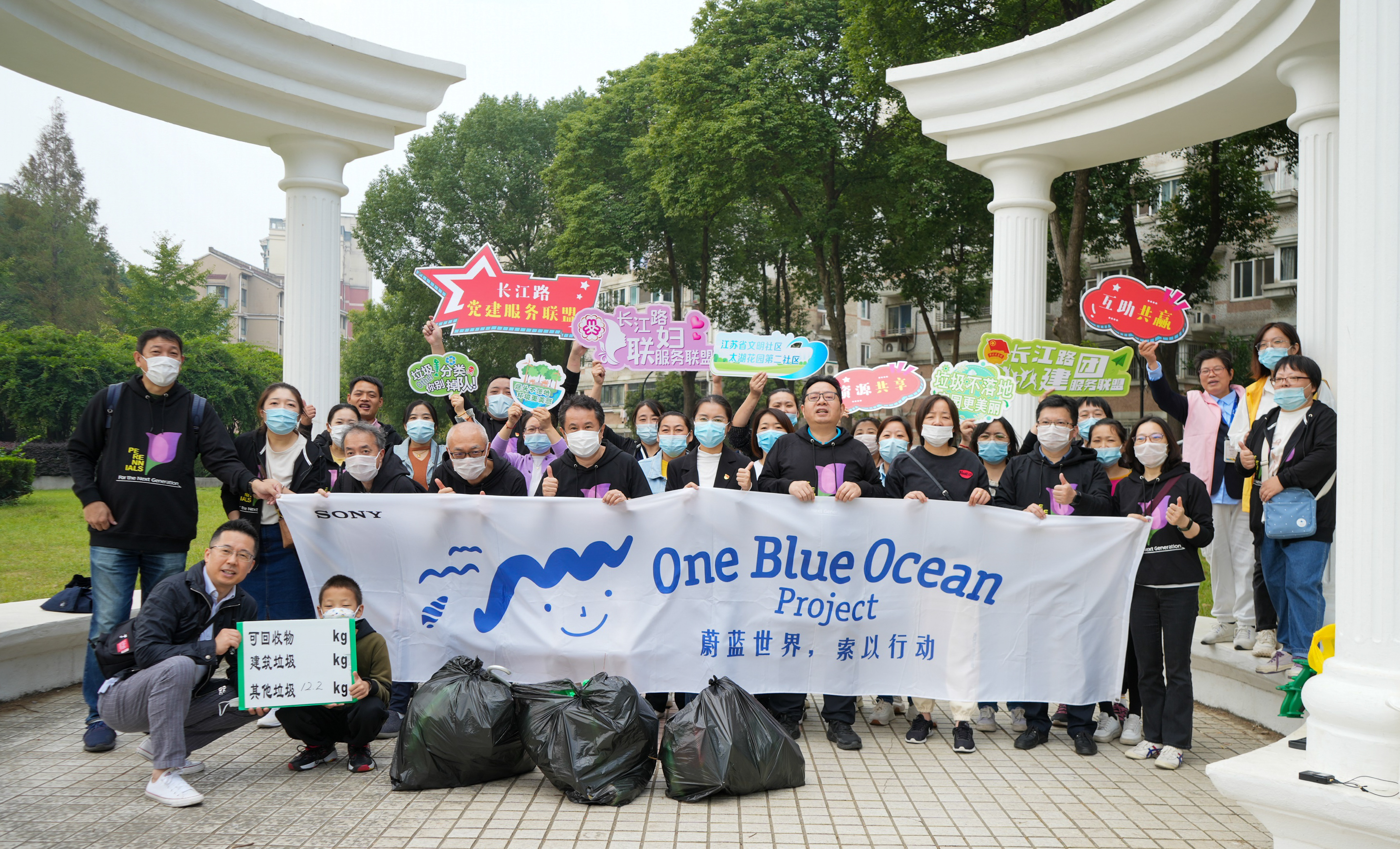 屋外で「One Blue Ocean」の横断幕をもって記念写真に写る人々