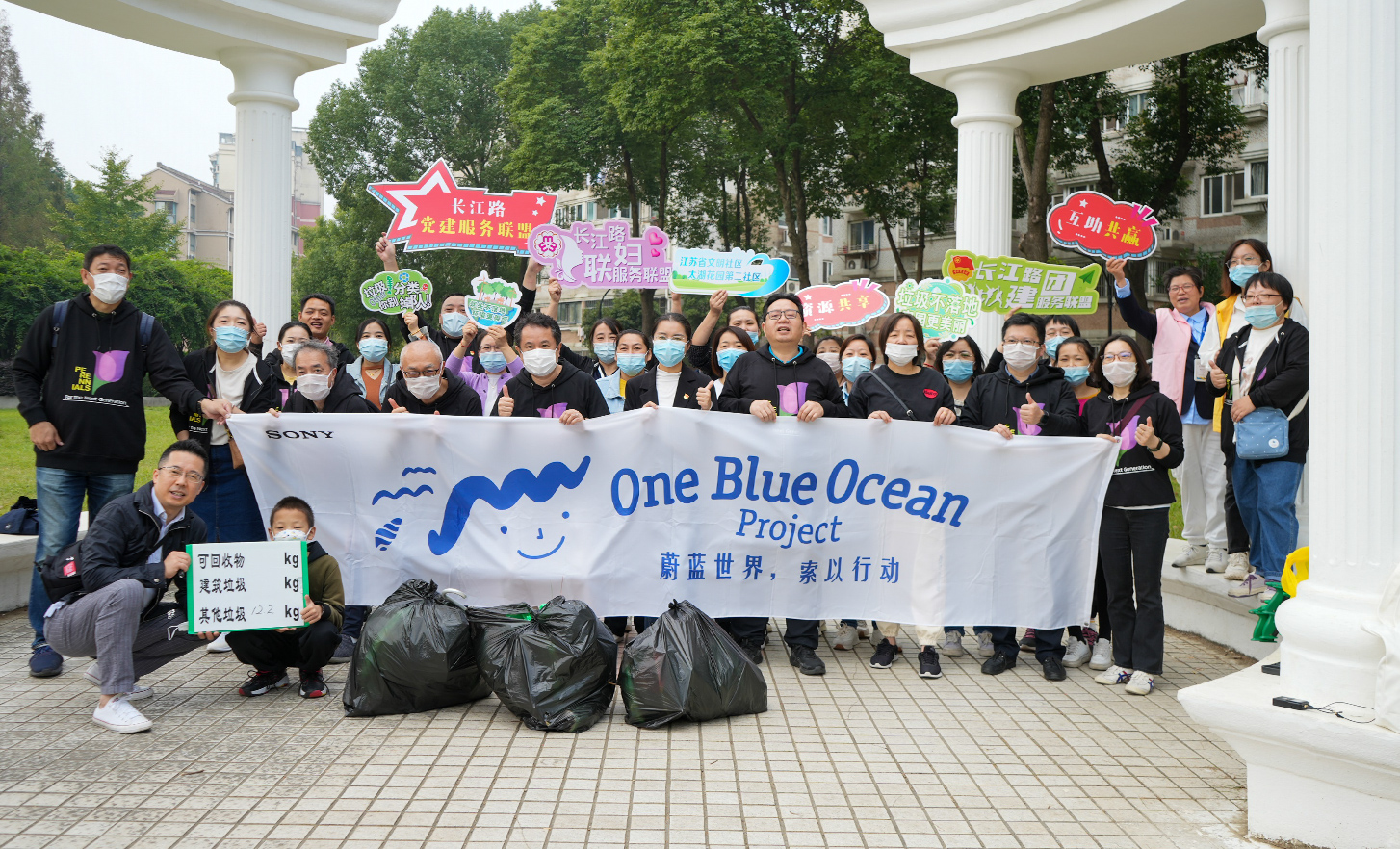 屋外で「One Blue Ocean」の横断幕をもって記念写真に写る人々