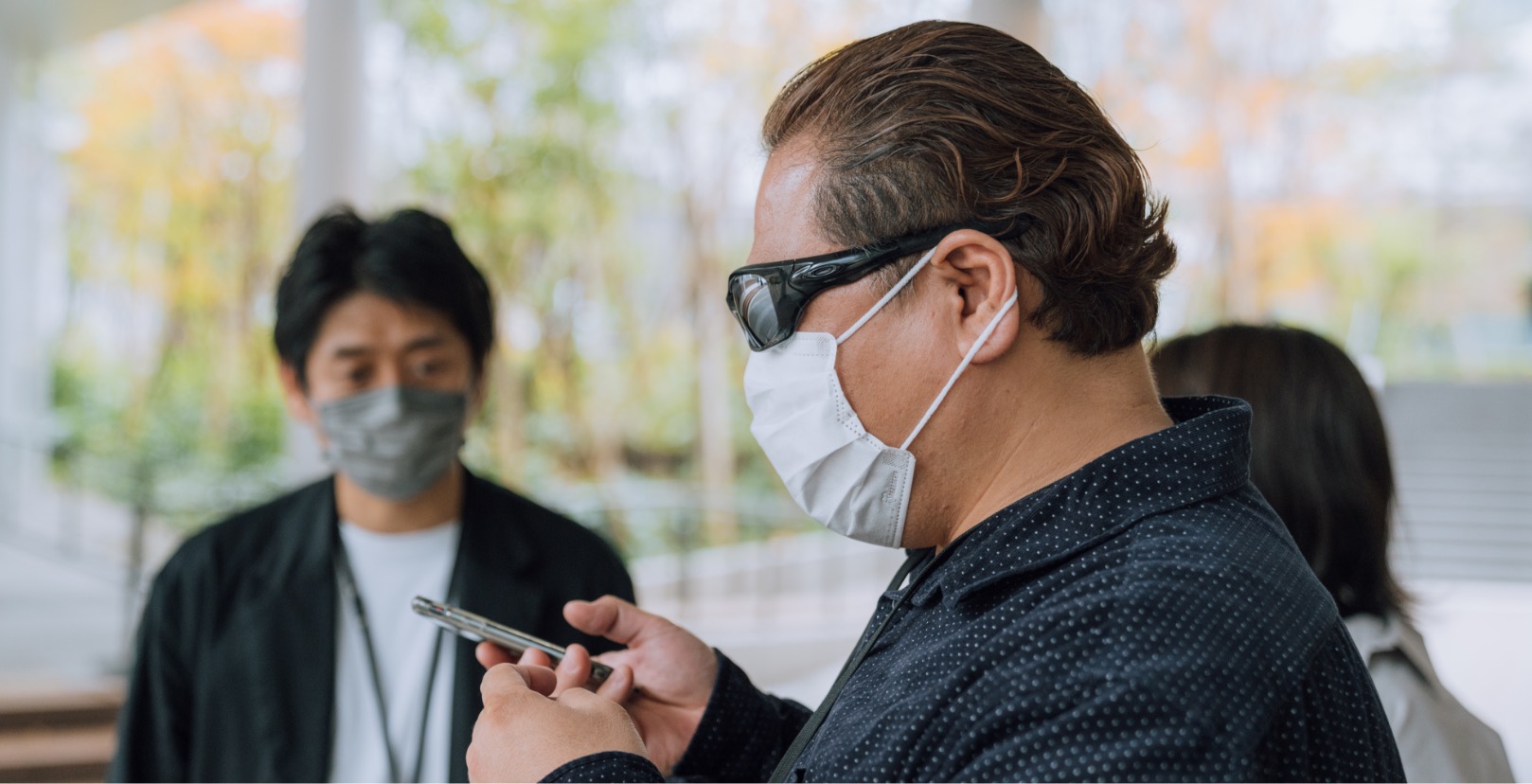 A picture containing person wearing sunglasses, using a smartphone