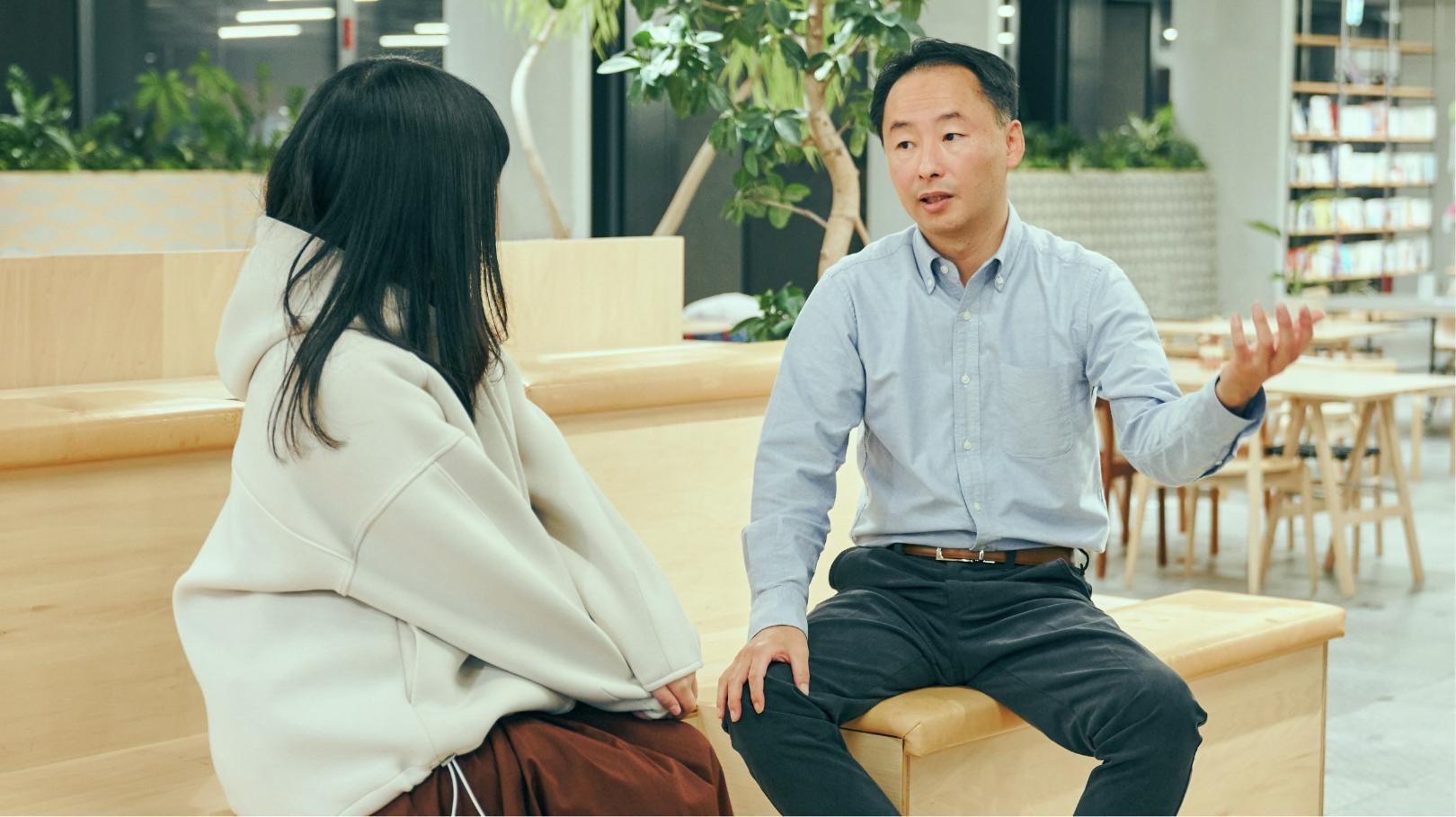 Haruko Miki and Mitsunori Tanaka sitting on benches talking to each other