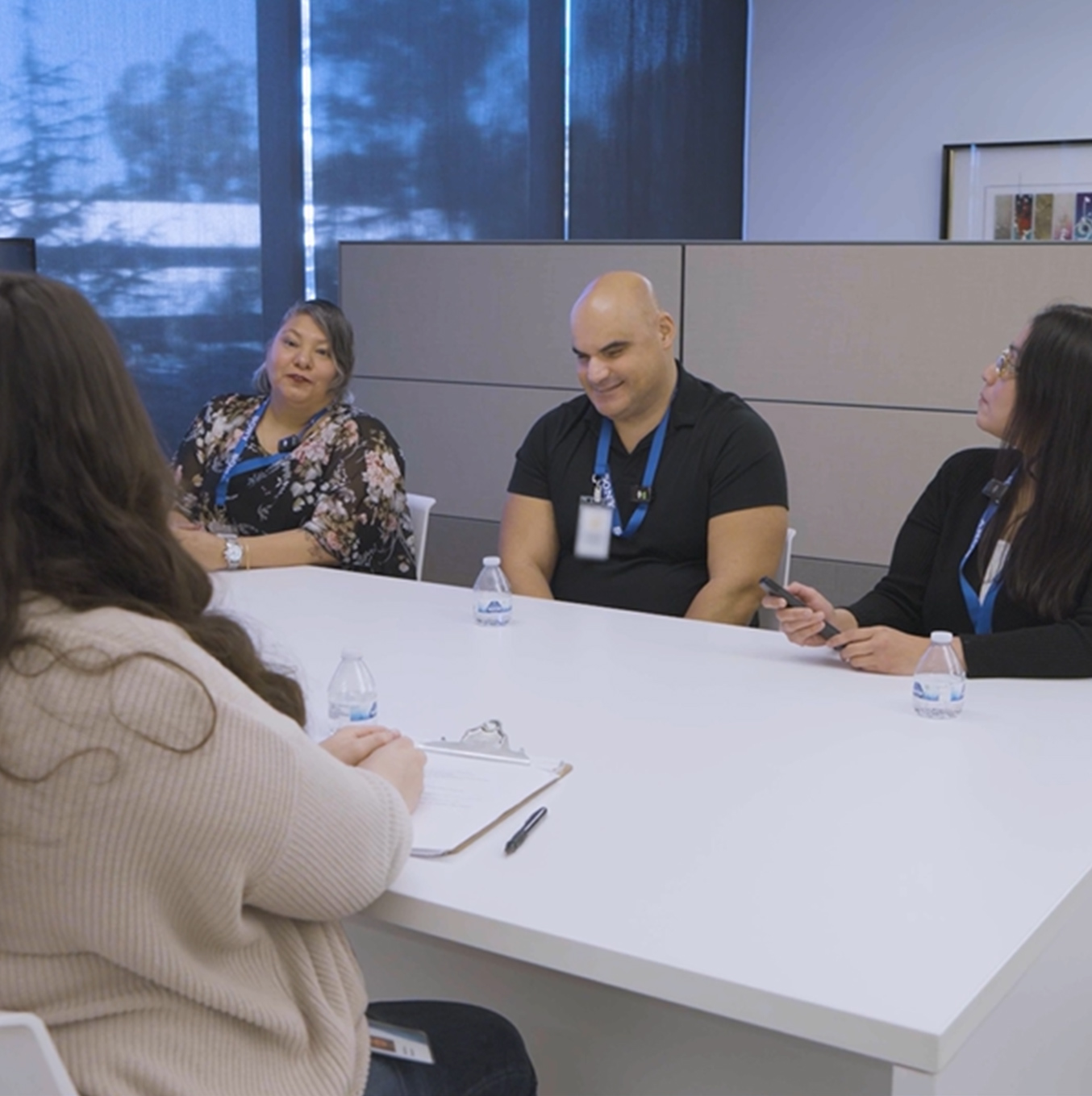 Image showing three people sitting at a table, being interviewed by a woman who has a clipboard and pen