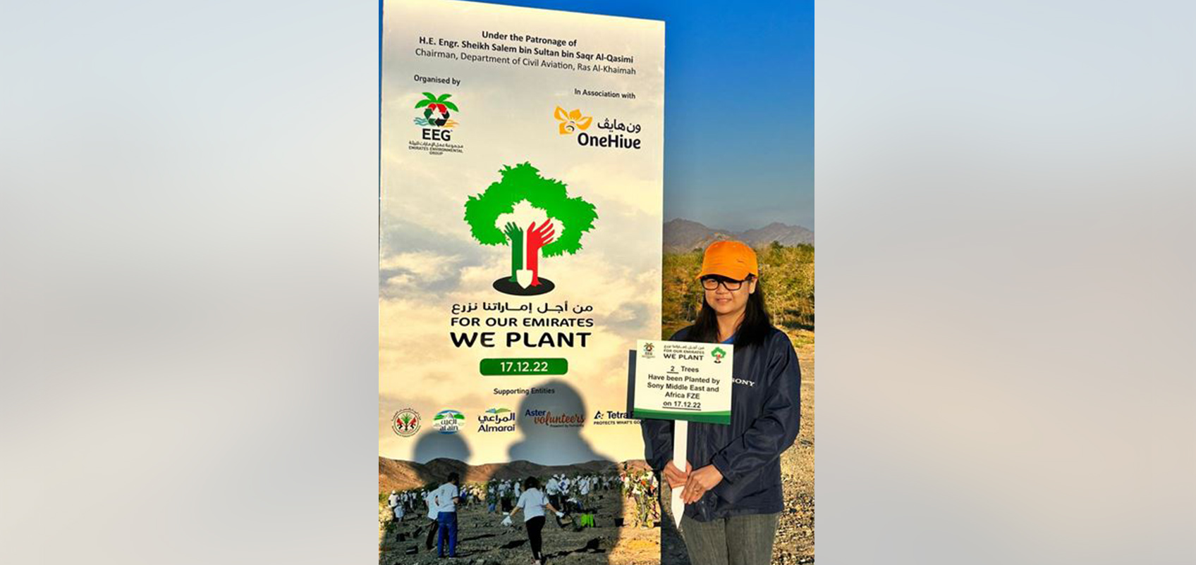 An employee stands in front of the "We Plant" flag