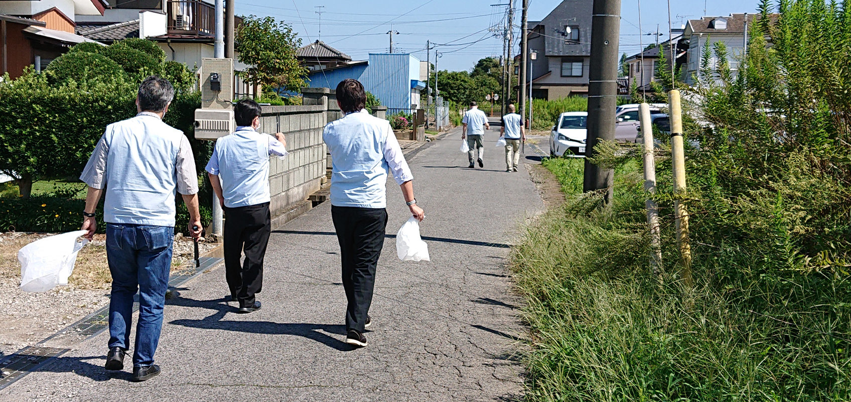 Employees picking up trash along the side of the sidewalk