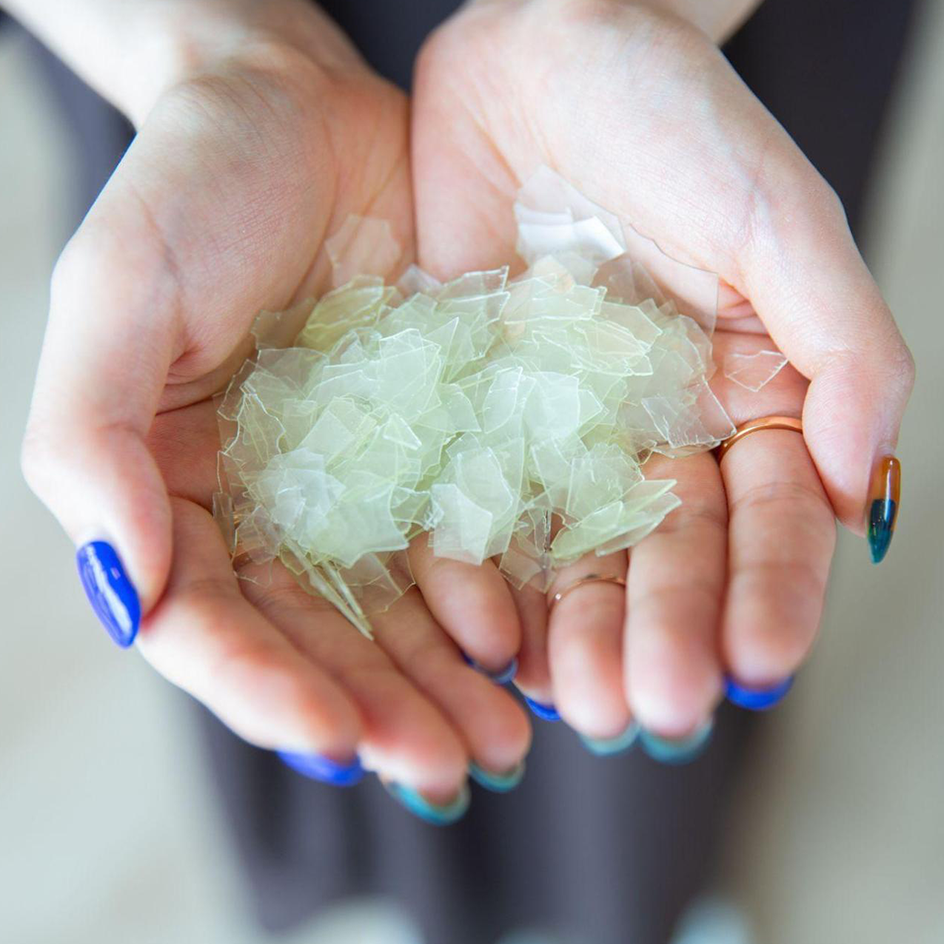 Pieces of thin, white plastic in the palm of the hands